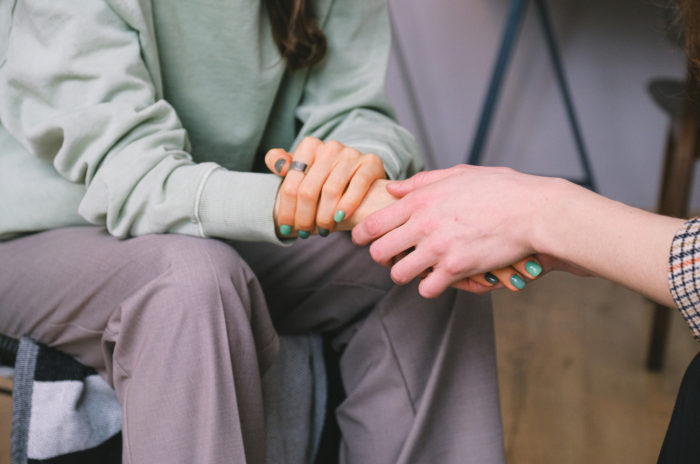 a woman holding another woman’s hand in a supporting way a woman holding another woman's hand in a supporting way